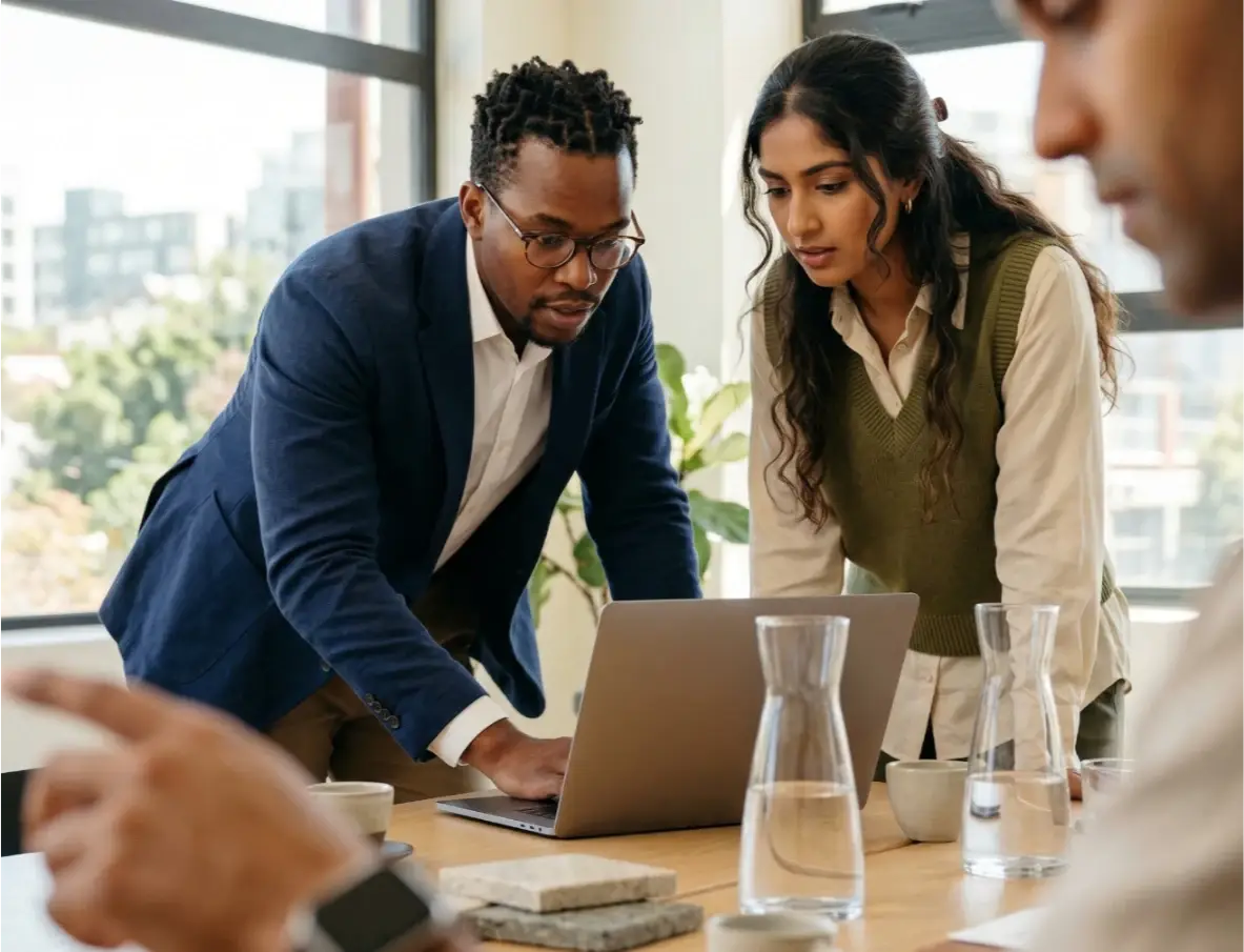 Team of professionals reviewing software licensing options on a laptop in a meeting room
